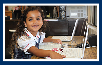 Smiling female student poses as she uses a laptop