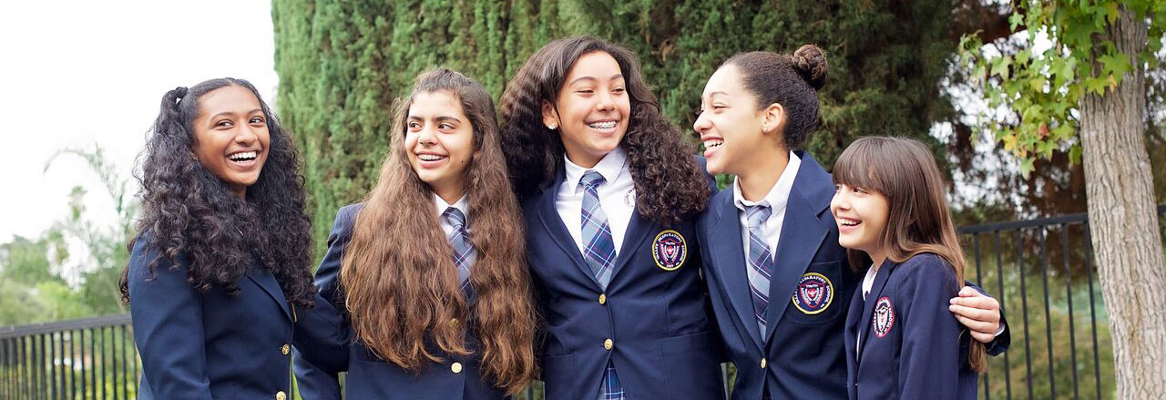 High school girls outside posing for a picture wearing school uniform